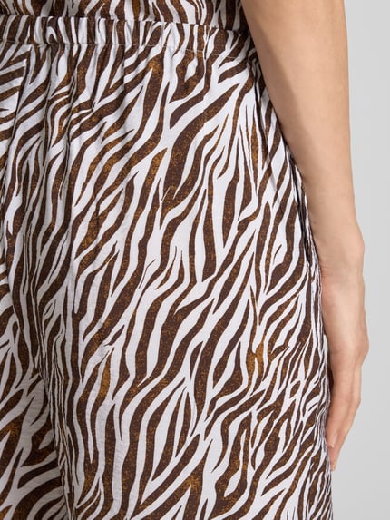 Frauenmodel trägt Stoffhose aus Viskose-Mix im Allover-Look Modell 'Mele' von FREE/QUENT, braun-weiße Muster, Nahaufnahme Hüfte, Kontext: Damen Stoffhose mit Tunnelzug, Wide Leg, Bundweite bei Größe S 39 cm, Innenbeinlänge 80 cm.