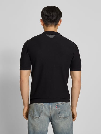 Männermodel trägt Slim Fit Poloshirt in Strick-Optik von Replay, reine Baumwolle, kurzärmelig, gerippte Abschlüsse, Ganzkörperansicht Rückansicht