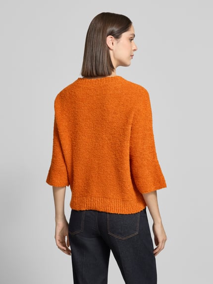 Vrouwenmodel draagt gebreide pullover met 3/4-mouw van Rich & Royal in oranje, materiaalmix met wol, regular fit, ruglengte maat S 56 cm, mouwlengte 20 cm, dames, detailrijke textuur, Ganzkörperansicht Rückansicht