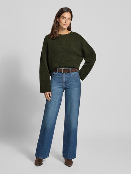 Vrouwenmodel draagt Relaxed fit gebreide pullover met ronde hals Model 'VITOW' van American Vintage, donkergroen, dames, ruglengte maat S 56 cm, mouwlengte maat S 57 cm. Ganzlichaansicht van voren.