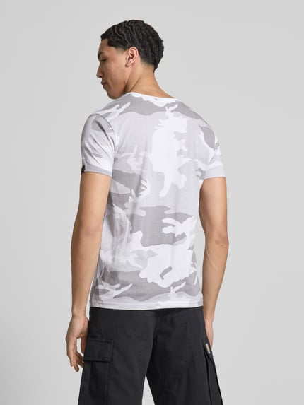 Männermodel trägt T-Shirt mit Label-Print von Alpha Industries in Weiß-Grau Camouflage, Reine Baumwolle, Gerader-Schnitt, Ganzkörperansicht Rückansicht. Rückenlänge bei Größe M: 70 cm, Rundhalsausschnitt.