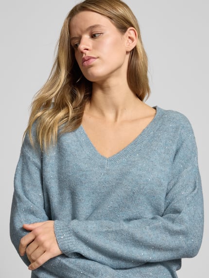 Frauenmodel trägt Regular Fit Strickpullover mit Paillettenbesatz Modell 'ARIZONA' von Only in melierter Optik, Nahaufnahme Oberkörper.