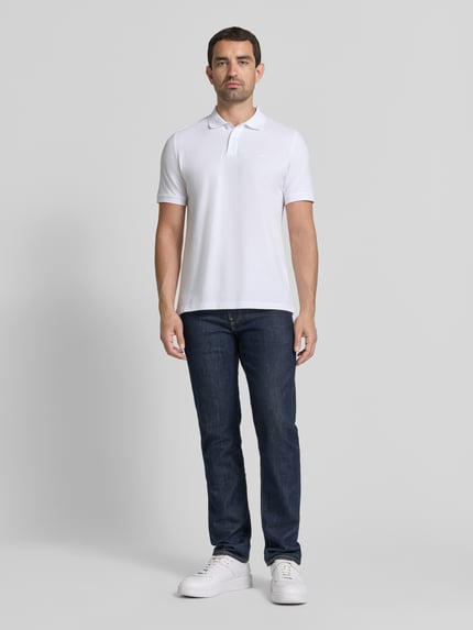 Männermodel trägt Regular Fit Poloshirt aus reiner Baumwolle von s.Oliver RED LABEL in Weiß, glatte Textur, Ganzkörperansicht von vorne.
