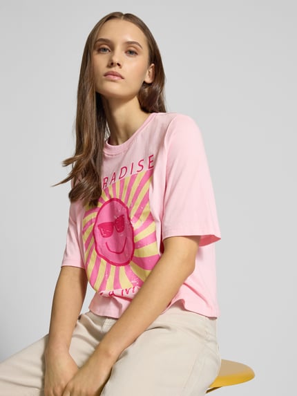Vrouwenmodel draagt relaxed fit T-shirt uit puur katoen model 'CARTY' van ONLY, look: effen met motiefprint, korte mouw, ronde hals, jersey. Nahaufnahme Oberkörper.