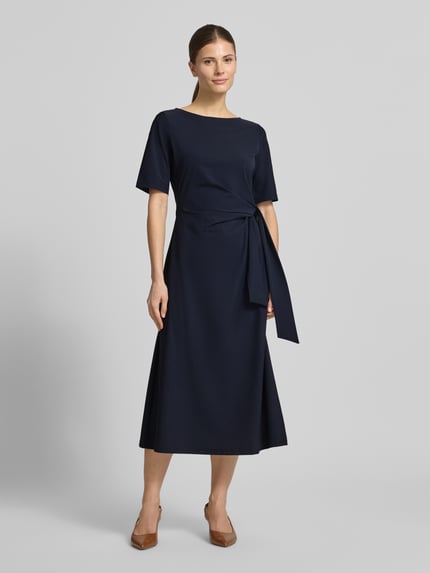 Modelka kobieca nosi Midikleid mit Knotendetail von Milano Italy, ciemnogranatowy, taillowany krój, materiał z elastanem, widoczne wiązanie w talii, okrągły dekolt, długość tyłu w rozmiarze 36: 44 cm, szerokość w rozmiarze 36: 33 cm, długość rękawa w rozmiarze 36: 29 cm, widok całej sylwetki z przodu