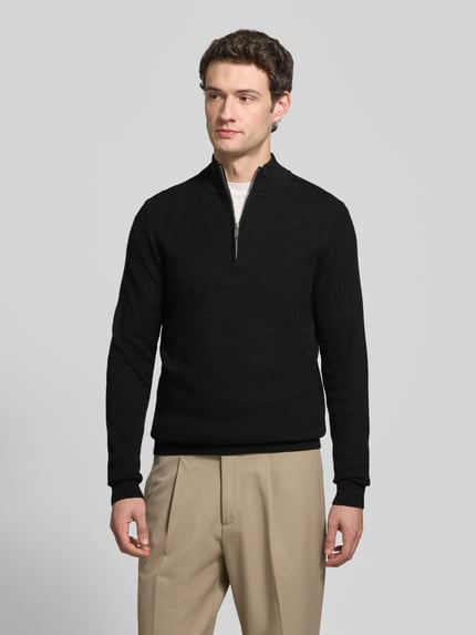 Männermodel trägt Slim Fit Strickpullover aus Baumwoll-Mix mit Troyer-Kragen von Profuomo, beige Hose, elastische Abschlüsse, Ganzkörperansicht von vorne.