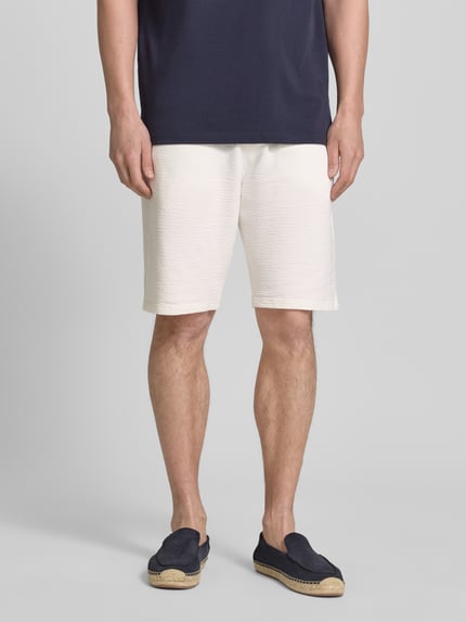 Männermodel trägt Relaxed Fit Bermudas aus Baumwoll-Mix Modell 'DETROIT' von s.Oliver RED LABEL, unifarben, Waffelstruktur, Ganzkörperansicht von vorne.