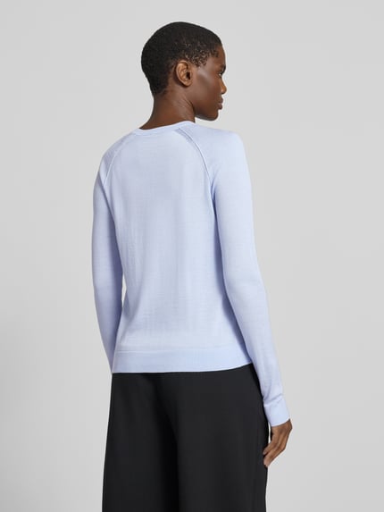 Frauenmodel trägt Strickjacke aus Wolle mit Rundhalsausschnitt von BOSS, unifarben, langarm, gerippter Rumpfabschluss, Ganzkörperansicht Rückansicht.