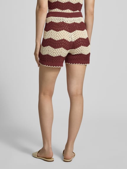 Vrouwenmodel draagt Regular Fit Shorts uit zuiver katoen model 'GOLDEN COVE' van Vero Moda met gebreide streeplook, elastische tailleband en gebreide textuur, kleuren bordeauxrood en beige, achteraanzicht volledige lichaamsopname.