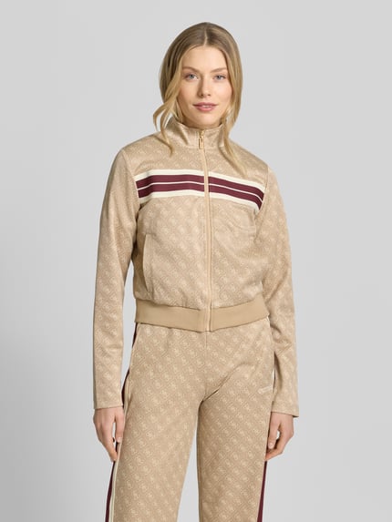 Frauenmodel trägt Regular Fit Sweatjacke mit Allover-Logo-Print Modell 'Jacquard' von Guess, beige mit roten Streifen, Material-Mix, Nahaufnahme Oberkörper.
