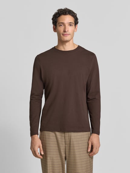 Männermodel trägt Langarmshirt mit Rundhalsausschnitt von S.OLIVER CASUAL, unifarben braun, glatte Textur, Ganzkörperansicht von vorne.