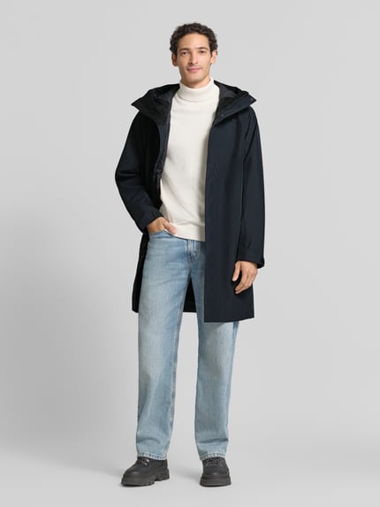 Męski model nosi Regular Fit Parka mit Kapuze Model 'Treeline HIPE' od Peak Performance, czarny kolor, gładka tekstura, krój regular fit, kaptur, zamek błyskawiczny zakryty, Długość tyłu w rozmiarze M: 99 cm, szerokość ramion w rozmiarze M: 54 cm, szerokość klatki piersiowej w rozmiarze M: 60 cm, długość rękawów w rozmiarze M: 61 cm, widok całej sylwetki z przodu.