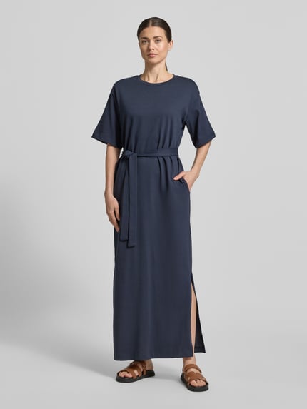 Frauenmodel trägt Loose Fit Maxikleid aus reiner Baumwolle Modell 'ESSENTIAL' von Selected Femme, unifarben, mit Bindegürtel, Ganzkörperansicht von vorne.