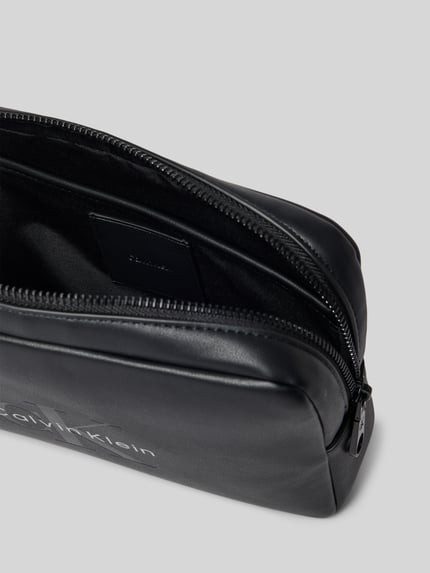 Produktfoto, schwarze Henkeltasche mit Label-Prägung von CK Calvin Klein für Herren, glatte Oberfläche, silberner Zip, Innenfach sichtbar.