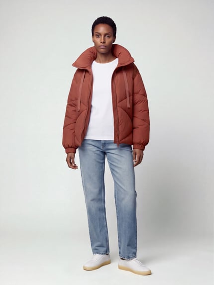 Frauenmodel trägt Pufferjacke mit großer Kapuze von JAKE*S WOMAN CASUAL, rostbraun, Rautenstruktur, Elastikabschlüsse, Front-Zweiwege-Reißverschluss, seitliche Taschen, Ganzkörperansicht von vorne.