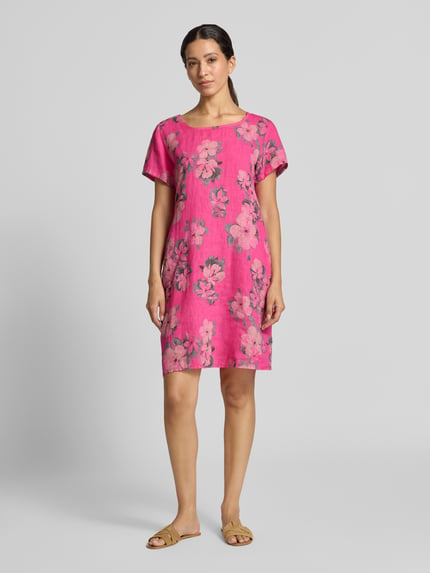 Frauenmodel trägt Leinenkleid in Minilänge Modell 'Miraa' von ZABAIONE in Pink mit Blumenmuster, leicht tailliert, Ganzkörperansicht von vorne. Damen Leinenkleid aus elastischem Leinen-Baumwoll-Mix mit Rundhalsausschnitt, kurzen Ärmeln und Minilänge.