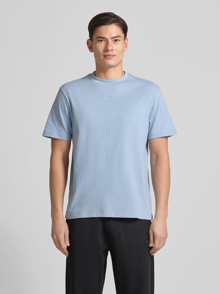 Männermodel trägt Relaxed Fit T-Shirt aus reiner Baumwolle Modell 'DAPOLINO' von HUGO in Hellblau, unifarben, Label Print, Ganzkörperansicht von vorne.
