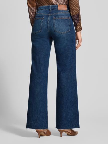 Frauenmodel trägt Flared Fit Jeans aus elastischem Baumwoll-Mix mit Gürtelschlaufen von Luisa Cerano, dunkelblau, Ganzkörperansicht Rückansicht. Innen Beinlänge 83 cm, Eingrifftaschen, Gesäßtaschen, Knopf- und Reißverschluss, Bundweite 39 cm.