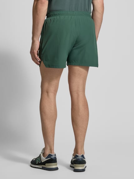 Mężczyzna model nosi szorty z elastycznym pasem od HALO, mieszanka materiałów z dodatkiem streczu, krój regular fit, nadruk z logo, zielony kolor, szerokość w rozmiarze M: 40 cm, długość wewnętrzna nogawki w rozmiarze M: 12 cm, zdjęcie całej sylwetki z tyłu.