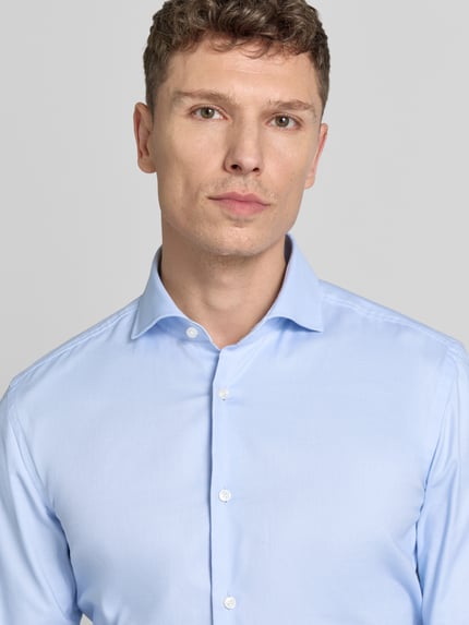 Männermodel trägt Regular Fit Businesshemd mit extra langem Arm van BOSS, lichtblauw, katoenmix, haifischkraag, knoopsluiting, unicolor, nahaufnahme oberkörper.