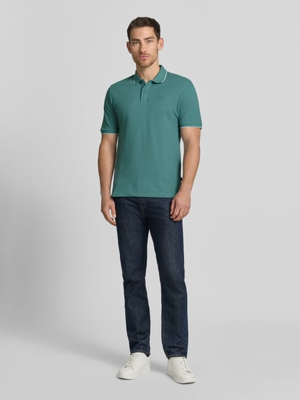 Mężczyzna nosi Slim Fit Poloshirt mit Stitching von Jack & Jones Premium, bawełna, krój slim fit, zapięcie na guziki, zielony, widok całej sylwetki z przodu.