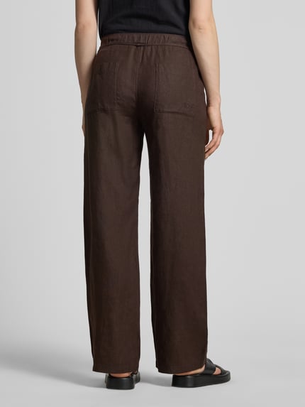 Frauenmodel trägt Leinenhose mit Bindegürtel Modell 'Chiara' von MAC, Reine Leinen, Wide-Fit, braun, Struktur sichtbar, Ganzkörperansicht Rückansicht.