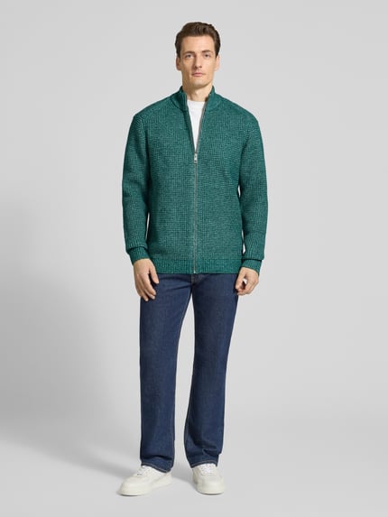 Männermodel trägt Regular Fit Strickjacke mit Woll-Anteil von Tom Tailor, grüne Melange-Optik, Reißverschluss, Stehkragen, Ganzkörperansicht von vorne.