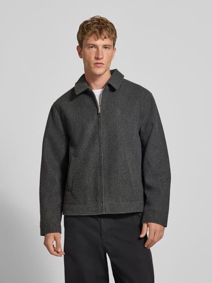 Männermodel trägt Jacke mit Label-Stitching von REVIEW in Dunkelgrau mit Reißverschluss und Umlegekragen, Ganzkörperansicht von vorne. Rückenlänge 67 cm, Schulterbreite 50 cm, Brustweite 59 cm, Ärmellänge 64 cm, Regular Fit.