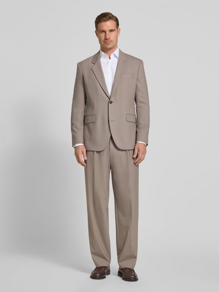 Męski model nosi Regular Fit Anzugsakko mit Viskose-Anteil Modell 'Karlo243X' von HUGO, efekt: jednolity kolor, splot twill, mieszanka materiałów z dodatkiem wiskozy, krój regular fit, kołnierz z połami, zapięcie na 2 guziki, długi rękaw, nachodzące na siebie guziki, wykończenie z rozcięciami po bokach, brustasza i kieszenie z patką, kolor beżowy, całkowity widok z przodu.