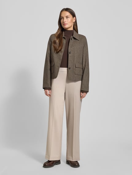 Frauenmodel trägt Wide Leg Hose mit Viskose-Anteil Modell 'EMMA-TARA' von Selected Femme, Optik: Unifarben, Passform: Wide Leg, Applikation: Label-Stitching, Bundabschluss: Elastisch, seitliche Eingrifftaschen, Ganzkörperansicht von vorne.