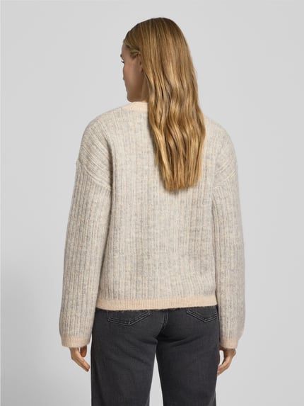 Frauenmodel trägt Relaxed Fit Strickpullover aus Woll-Mix mit Alpaka-Anteil Modell 'FALVA' von Selected Femme, Strukturmuster in Beige-Grau, gerippte Bündchen, Ganzkörperansicht Rückansicht.