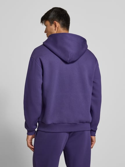 Männermodel trägt Relaxed Fit Sweatjacke aus Baumwoll-Mix mit Label-Detail von REVIEW in Lila, glatte Textur, Ganzkörperansicht Rückansicht.