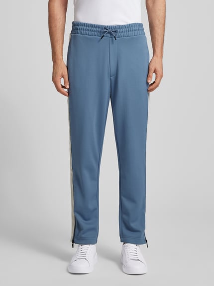 Męski model nosi Relaxed Fit Jogginghose mit Galonstreifen Modell 'DOLOS' od HUGO, efekt: jednolity kolor, lampasy, dzianina dresowa, wpuszczane kieszenie, tunel, elastyczny ściągacz; Ganzkörperansicht von vorne.