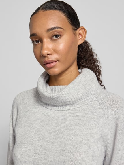 Frauenmodel trägt Rollkragenpullover mit weitem Kragen von ONLY in Hellgrau, Strukturstrick, Regular Fit, Nahaufnahme Oberkörper.