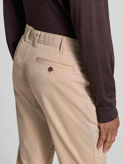 Männermodel trägt Slim Fit Stoffhose mit Viskose-Anteil von MCNEAL, Beige, Elastischer-Material-Mix, Gesäßtaschen, Nahaufnahme Rückansicht.