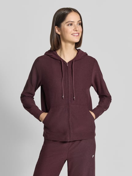 Frauenmodel trägt Regular Fit Sweatjacke Logo-Print von Fabletics in Dunkelrot, hautsympathischer Material-Mix mit Stretch, elastische Abschlüsse, langer Arm, Logo vorne, Ganzkörperansicht von vorne.