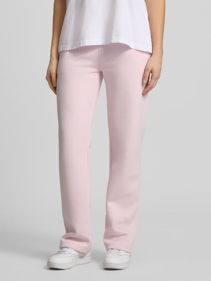 Frauenmodel trägt Sweatpants mit elastischem Bund Modell 'Iconic' von Gina Tricot in Rosa aus Baumwoll-Mix, Relaxed-Fit, Ganzkörperansicht von vorne. Damen Sweatpants, Innenbeinlänge bei Größe S 80 cm.