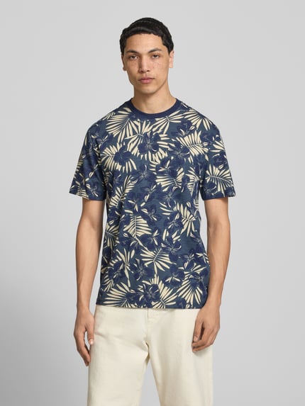 Męski model nosi Regular Fit T-Shirt aus reiner Baumwolle Modell 'PERRY' von Only & Sons, niebieski z kremowym wzorem liści, jersey, krój regular fit, optyka allover, okrągły dekolt, krótki rękaw, Ganzkörperansicht von vorne