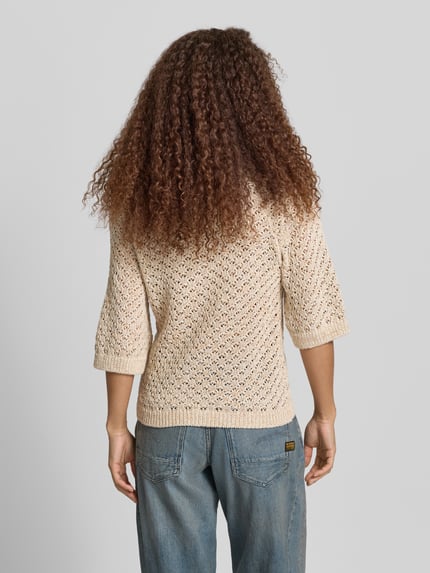 Männermodel trägt Boxy Fit Strickpullover aus Baumwoll-Mix Modell 'AMBER' von Pepe Jeans, kremowy, imitacja dzianiny, faktura, aplikacja z metką, krótki rękaw, ażur, widoczne wykończenie prążkowane, Ganzkörperansicht Rückansicht.