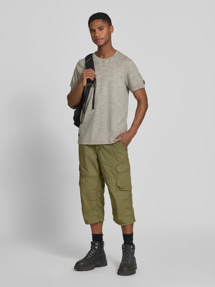 Männermodel trägt Regular Fit Capri-Bermudas mit Cargotaschen von camel active aus Reine Baumwolle, Label-Detail, Ganzkörperansicht von vorne.