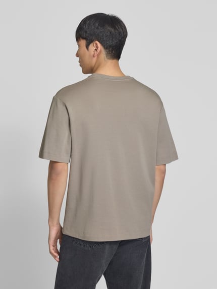 Męski model nosi T-Shirt mit Logo-Print und Rundhalsausschnitt od Profuomo z bawełny ekologicznej, krój relaxed fit, całkowity tył.
