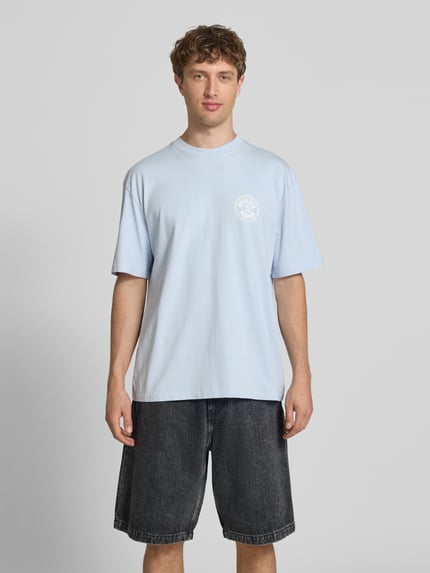 Männermodel trägt Oversized T-Shirt mit Label-Print von Pegador in Hellblau aus Reine Baumwolle, Rundhalsausschnitt, Herren T-Shirt, Ganzkörperansicht von vorne. Rückenlänge bei Größe M: 72 cm.