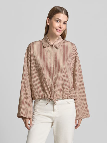 Vrouwenmodel draagt Boxy Fit Bluse aus Viskose-Mix Modell 'FIONEL' van DRYKORN met streeppatroon, overhemdkraag en tunnelkoord, frontale volledige lichaamsweergave.