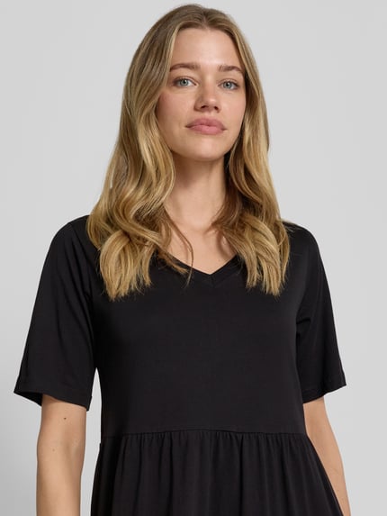 Frauenmodel trägt schwarzes Midikleid mit Smok-Detail, Rundhalsausschnitt, A-Linie aus Reine Baumwolle, Modell 'DERBY' von Soyaconcept, Nahaufnahme Oberkörper. Rückenlänge bei Größe S: 117 cm, Brustweite: 44 cm, Ärmellänge: 27 cm.