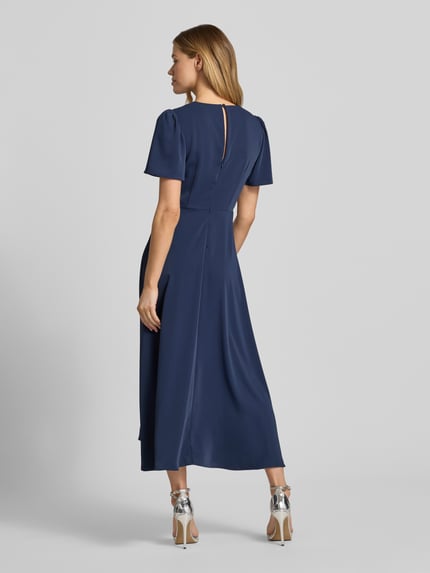 Kobiece model prezentuje 'Cocktailkleid mit V-Ausschnitt' od Christian Berg Cocktail, granatowy, gładka tkanina, długość midi, krój A-linii, dekolt V, węzeł, długość tyłu w rozmiarze 36: 128 cm, szerokość w rozmiarze 36: 40 cm, długość rękawa w rozmiarze 36: 26 cm, widok całej sylwetki z tyłu.