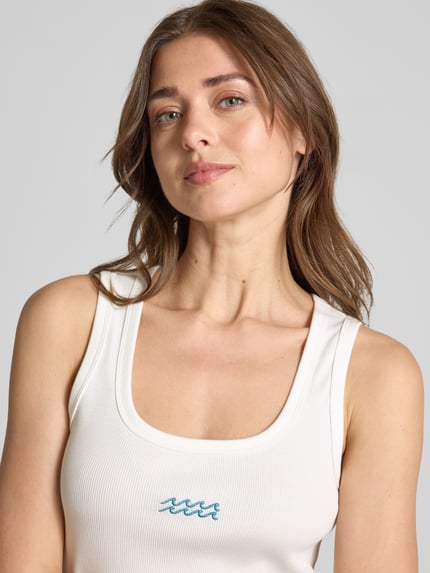 Vrouwenmodel draagt Slim Fit Tank Top uit mix van katoen en modal model 'DISA' van Vero Moda, effen kleuren, borduursel, rib, u-hals, brede bandjes, detailopname bovenlichaam.