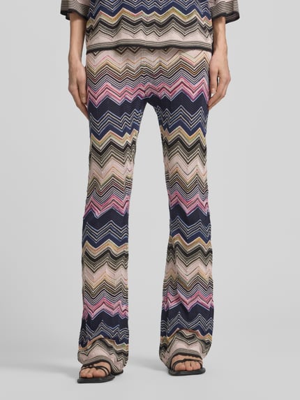 Männermodel trägt Flared Hose aus Viskose-Mix im Allover-Look von Oui, bunte Zickzackmuster, elastischer Bund, Szerokość w rozmiarze 36: 40 cm, długość nogawki wewnętrznej: 77 cm, Ganzkörperansicht von vorne