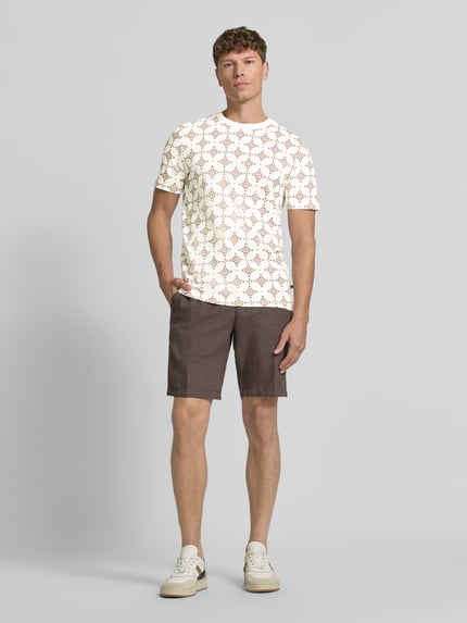 Männermodel trägt Regular Fit T-Shirt aus reiner Baumwolle von s.Oliver RED LABEL, wit met bruine print, bruine short, ganzkörperansicht von vorne