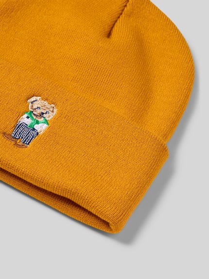 Productfoto, Mütze in Strick-Optik Modell 'BEAR' van CHILL PILL, mosterdgeel met gebreide structuur, brede omslag, motiefborduursel beer.