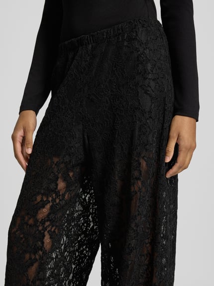 Frauenmodel trägt Wide Leg Hose aus Spitze Modell 'COCO' von Topshop, schwarz, florale Struktur, Material-Mix mit Stretch, Nahaufnahme Oberkörper.